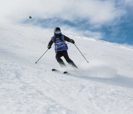 Pupil in a Schools Go Skiing bib carving down a wide piste