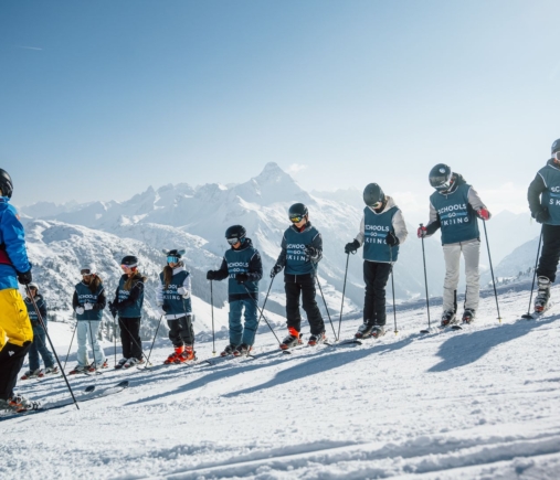 School ski group in Schools Go Skiing bibs lined up with the peaks behind
